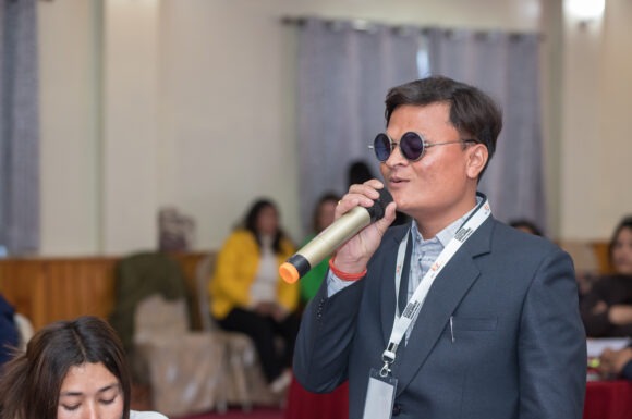 Bam Bahadur Bk, a young leader from Achham is holding a mic and actively participating in a program organized by Restless Development Nepal